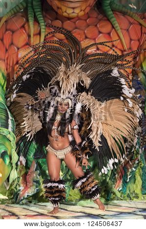 Parintis Brazil December 06 2015: Attractive smiling dancer woman in bikini and carnival feather costume bright brown colors and painted face in mask