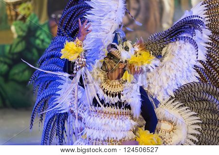 Parintis Brazil December 06 2015: Male carnival dancer in feather costume bright colors and painted face in mask