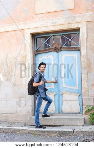 Handsome male tourist entering an old building (hostel, hotel or apartments). Traveling and couchsurfing concept.