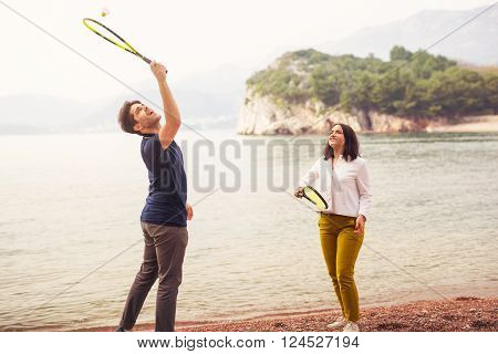 Two young people playing on the seashore speedminton - badminton