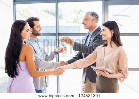 Real estate agent handing over house key to young couple in their new home
