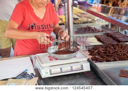 GEORGE TOWN MALAYSIA - MARCH 23: Woman cut and weigh Chinese dried pork on March 23 2016 on George Town Malaysia.