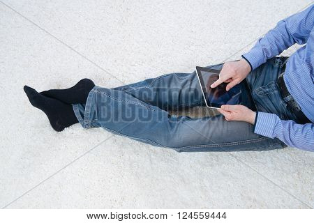 young man sitting on a white carpet with tablet