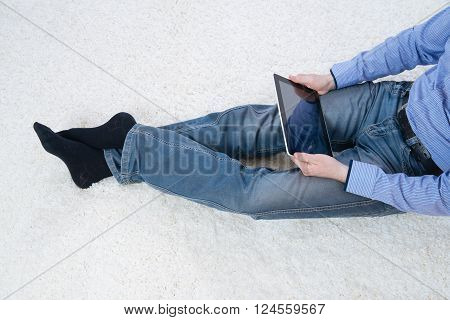 young man sitting on a white carpet with tablet