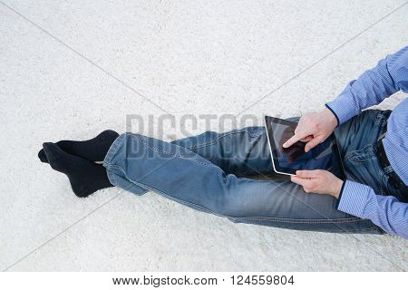 young man sitting on a white carpet with tablet