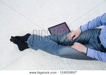 young man sitting on a white carpet with tablet