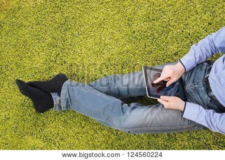 young man sitting on a green carpet with tablet