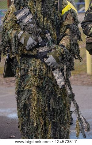 Sniper rifle in hands of sniper in camouflage ghillie suit