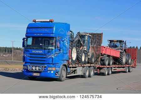 FORSSA, FINLAND - APRIL 2, 2016: Blue Scania truck hauls agricultural tractors and equipment on trailer at spring in South of Finland.