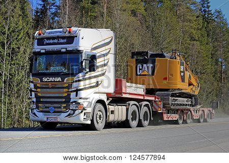 FORSSA, FINLAND - APRIL 2, 2016: Scania R560 V8 Truck hauls CAT 325F L Medium Hydraulic Excavator along highway.