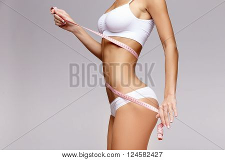 Slim tanned woman's body Isolated over gray background