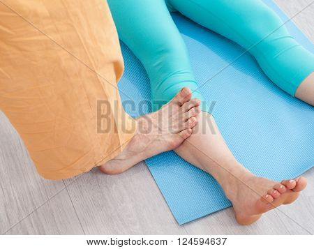 Thai massage session. Man presses on woman's leg by the foot
