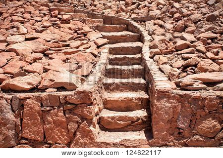 Clay red stone steps leading up a hill made of rocks and bending to the left.