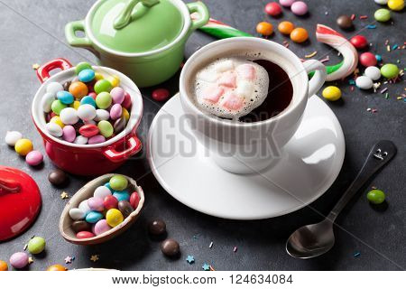 Colorful candies and coffee cup on stone background