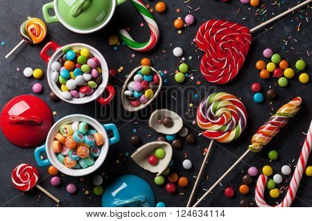 Colorful candies and lollypops on stone background. Top view
