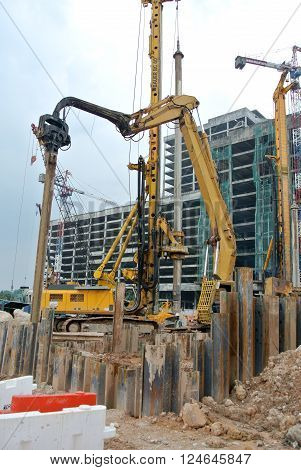 SELANGOR, MALAYSIA - MARCH 12, 2015: Sheet pile cofferdam driven machine at the construction site. This machine drove the sheet pile to the earth using vibrated hydraulic arm. Workers control.