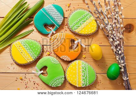 Easter homemade gingerbread cookie and yellow end green eggs over wooden table. Colorful image top view