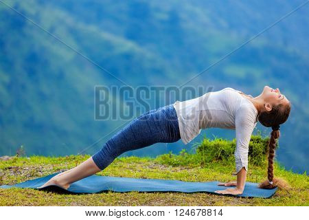 Woman doing Hatha yoga asana Purvottanasana plank pose  outdoors in mountains