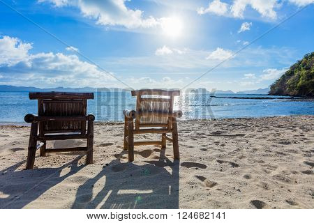 Two deckchairs on the tropical beach with bright sun