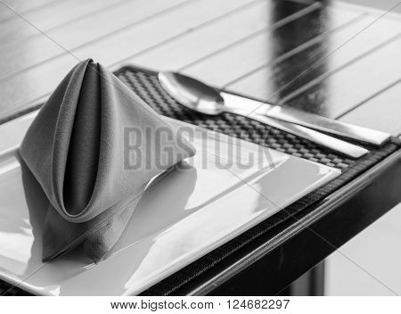 Folded napkin on white plate table setting in black and white image