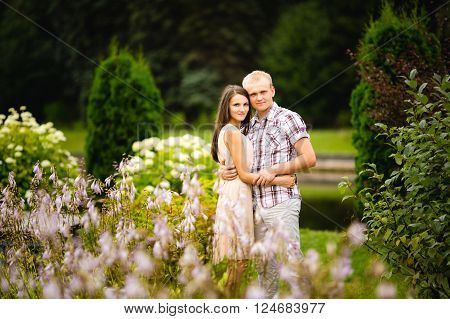 Cute couple lovely hugging in the garden flowers.