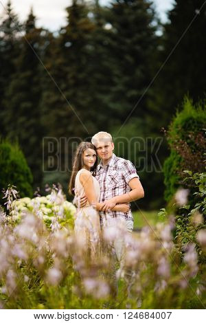 Cute couple lovely hugging in the garden flowers.