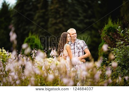 Cute couple lovely hugging in the garden flowers.