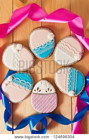 Easter homemade gingerbread cookie with pink and blue ribbon over wooden table. Colorful image top view