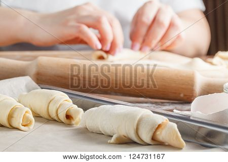 Woman hands making Croissant with Jam. Roll up.