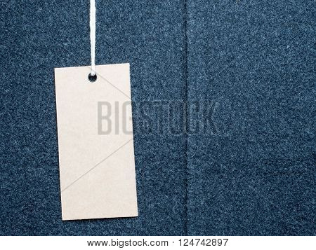 Blank paper price tag or label on black felt texture with fine detail