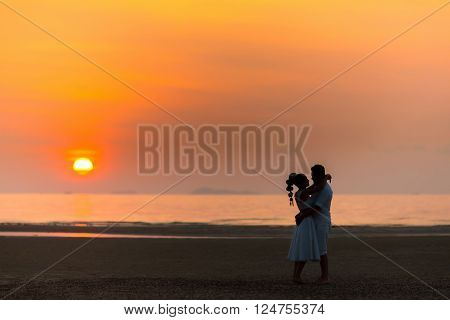 bride and groom on a tropical beach with the sunset in the background