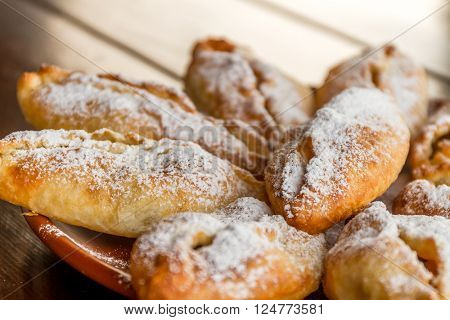 freshly baked apple pies on plate, wooden table