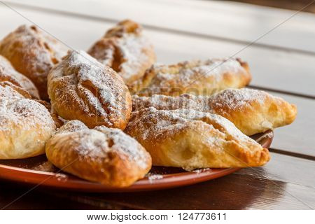 freshly baked apple pies on plate, wooden table