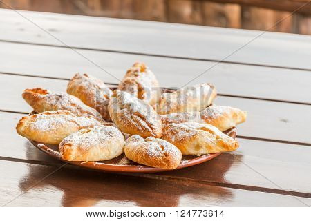 freshly baked apple pies on plate, wooden table