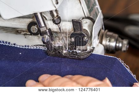 Work at the sewing machine stitching fabric edge at overlock