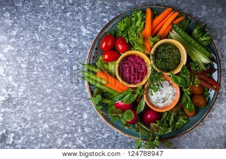 Veggie crudite platter with three different dips on the metal background