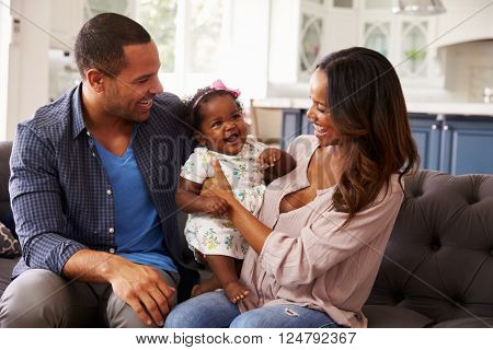 Happy parents with baby girl standing on mumÃÂ¢??s knee