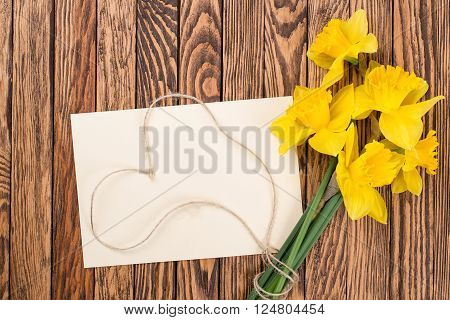 Spring yellow daffodils flowers and empty tag on the brown painted wooden planks. Selective focus. Place for text.