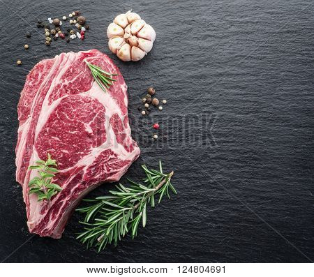 Rib eye steak with spices on the black background. 