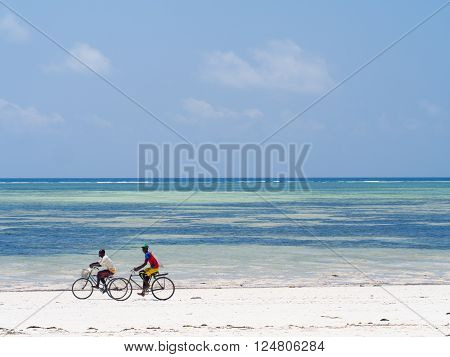 PAJE ZANZIBAR - MARCH 30 2016: Local people biking on the beach in Zanzibar Tanzania.