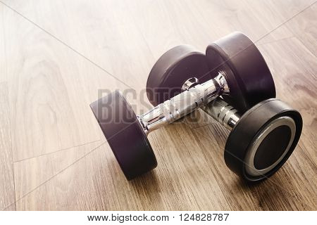 Dumbbells on wooden floor in gym Vintage tone