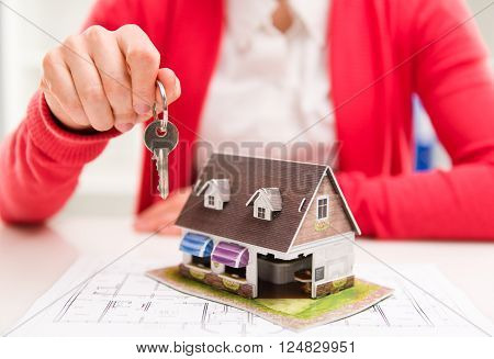 Young female makler holding key of new apartment. Real estate rent and sale concept. Shallow depth of field.