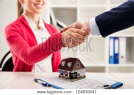 Business partnership. Female house agent greeting customer in the office. Shallow depth of field.