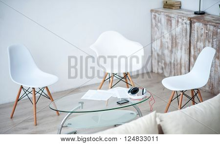 Nice furnishing. View of nice light room with white chairs standing around the glass little table