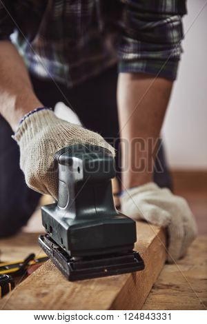 Male carpenter using electric planer for woodwork in joinery. Concept of DIY and furniture renovation.