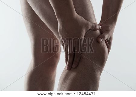 Closeup of young male massaging his sore knee. Joint disease treatment.