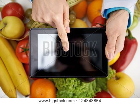 Close-up of doctor nutritionist pointing at smth on digital tablet screen. Weight loss and health care.