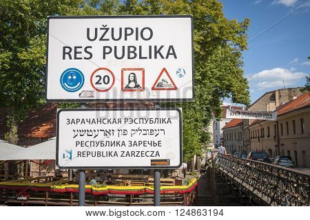 VILNIUS, LITHUANIA - JULY 15: Lithuanian road sign with text against of green tree and sky to enter Uzupis autonomous community. July 2015