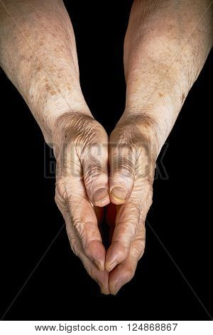 Old woman clasped in her hands on a black background