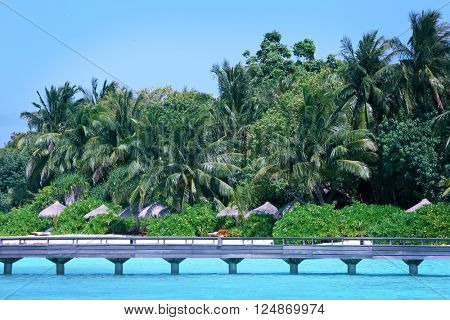 View of tropical Baros Maldives with sand beach and wooden bridge